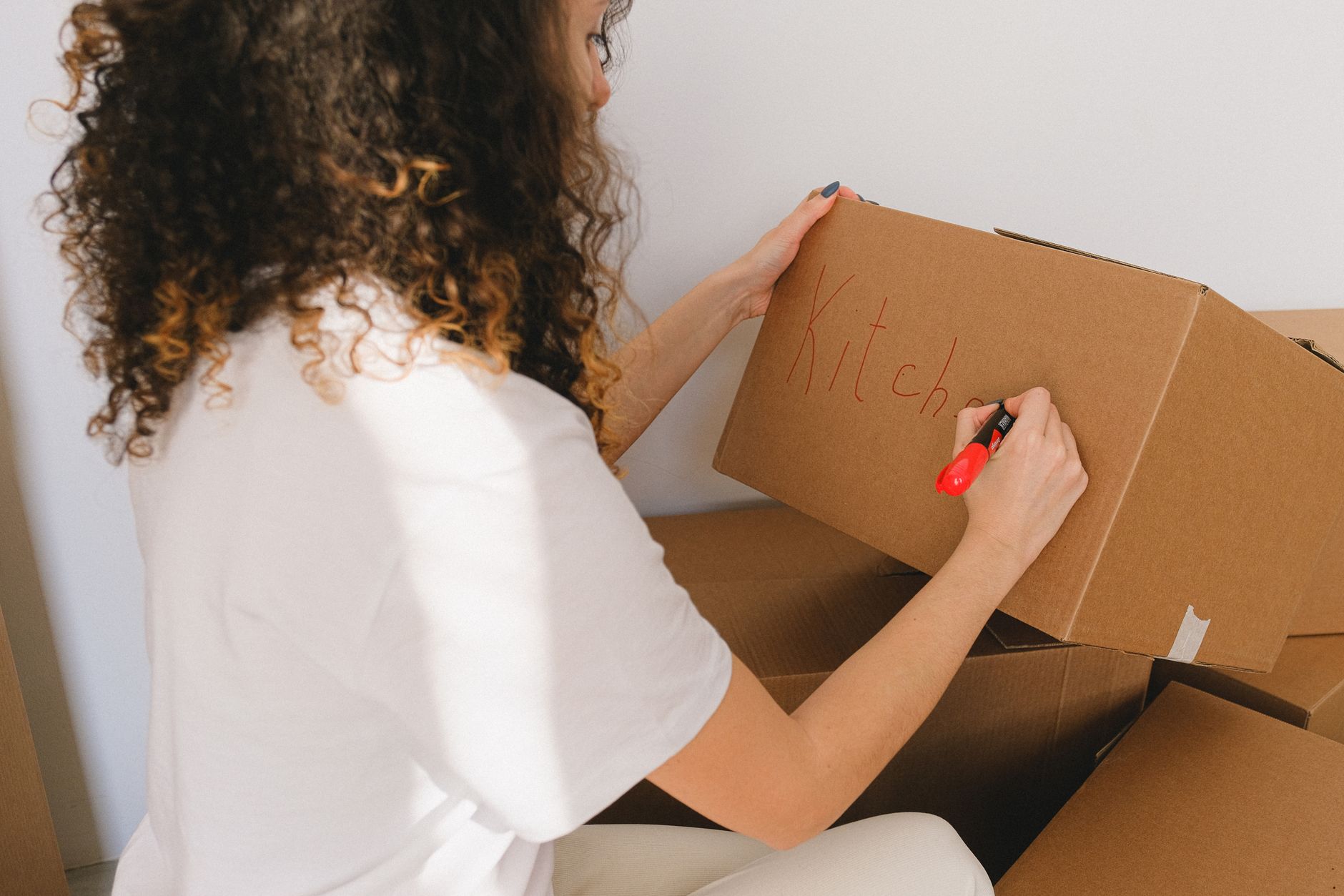 A woman labelling a cardboard box for the kitchen