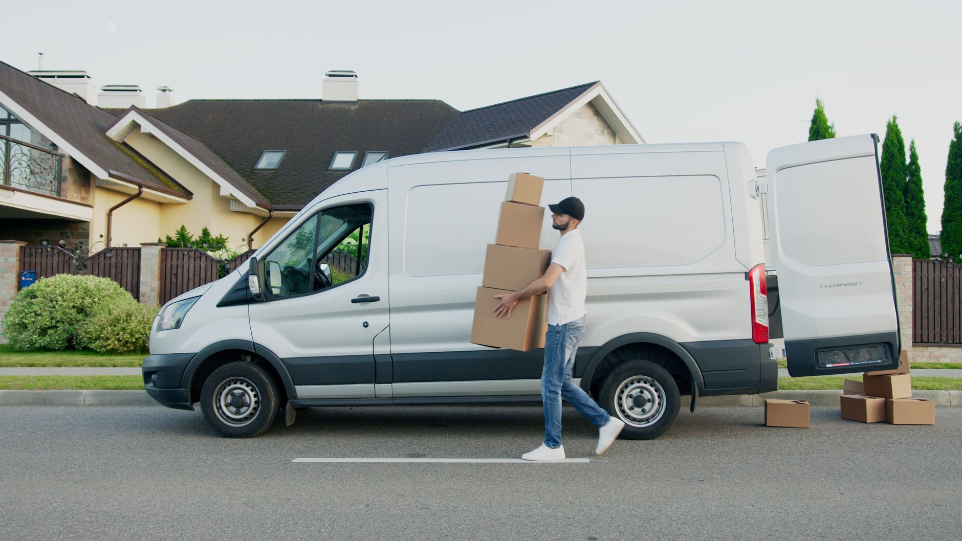 A man loading boxes into a white Transit van outside a house