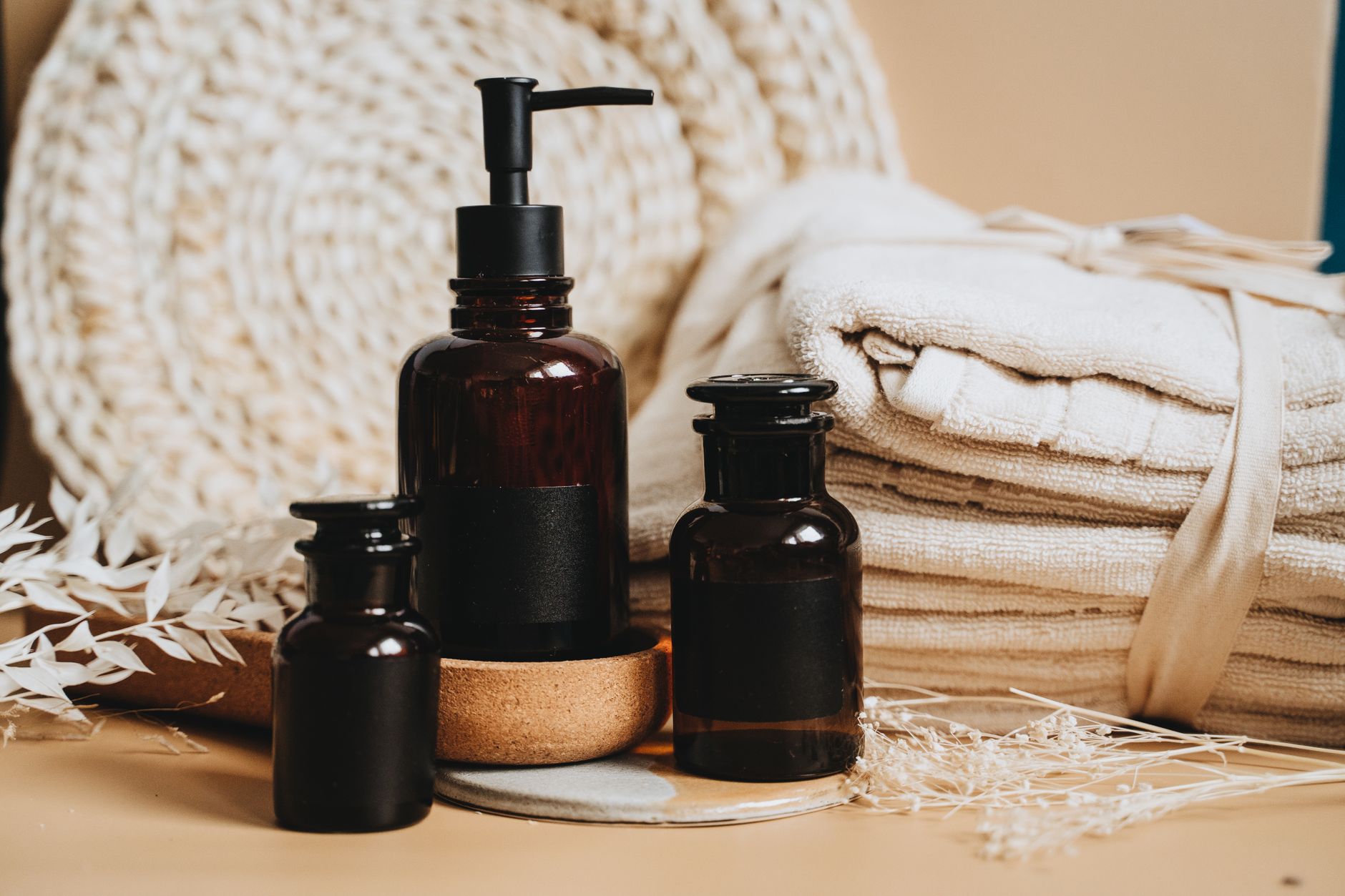 Brown glass toiletry bottles, including a pump bottle, beside folded beige towels