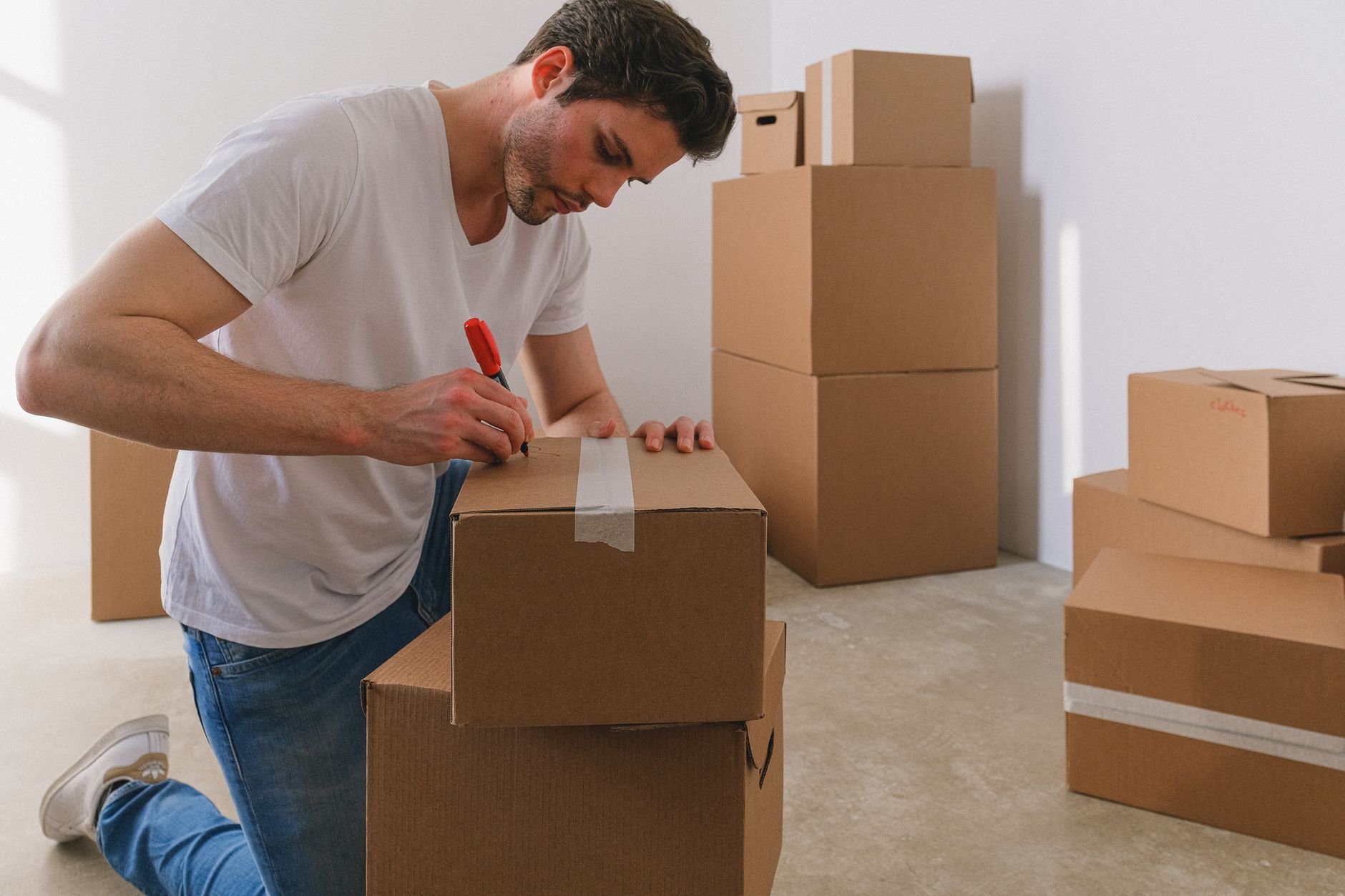 A man writing a room label on a sealed moving box