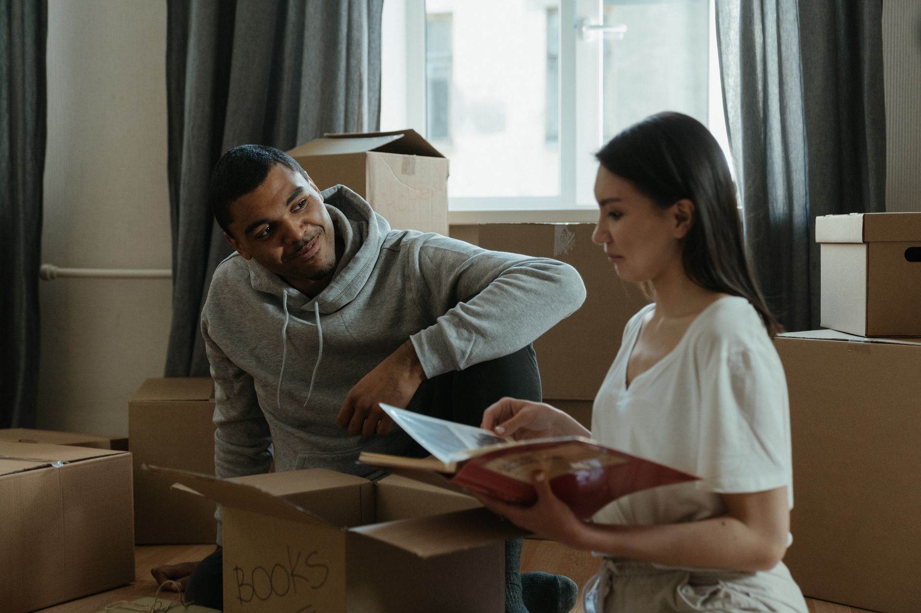 A couple sitting beside moving boxes and looking through a photo album
