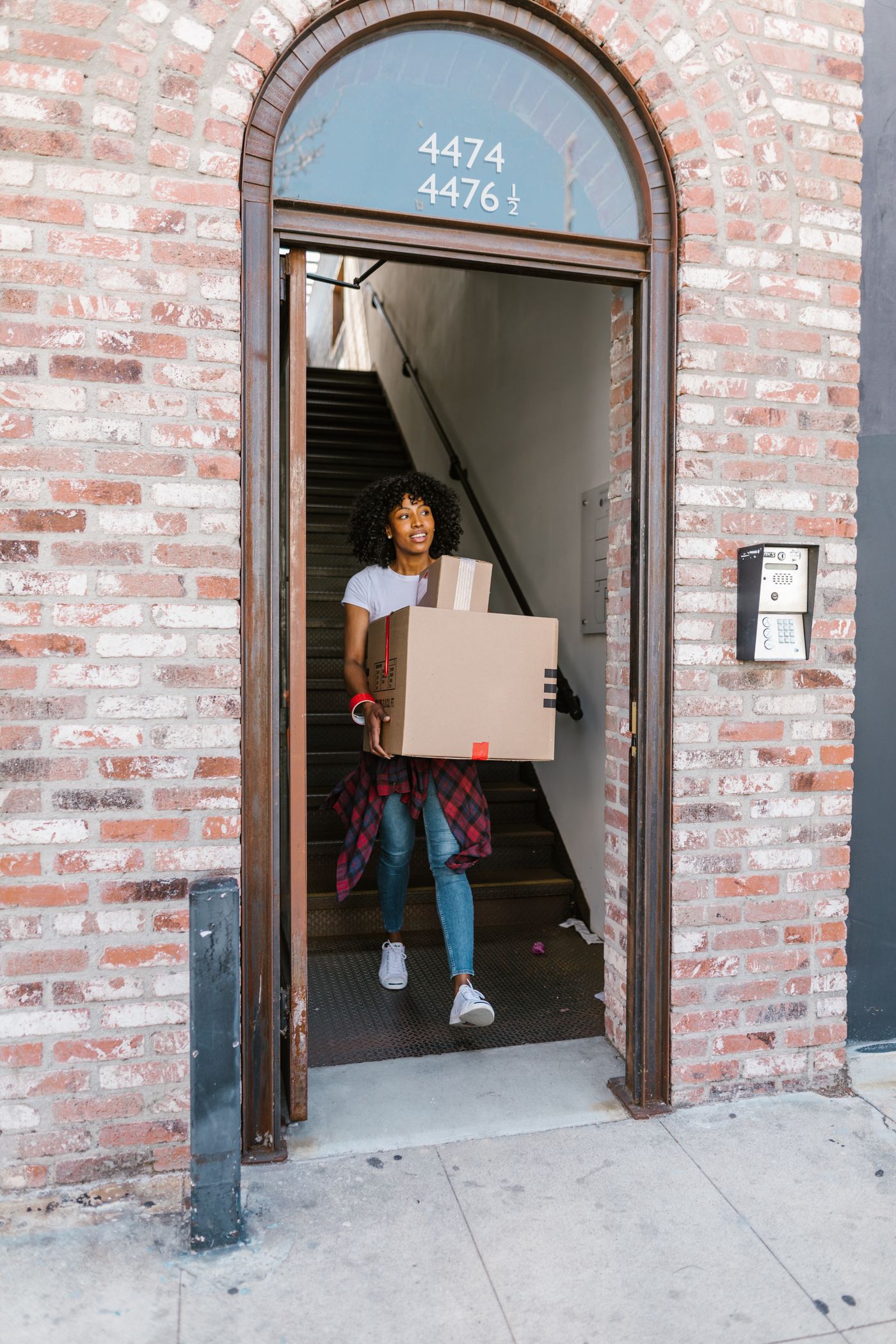 Woman carrying moving boxes out through an apartment entrance