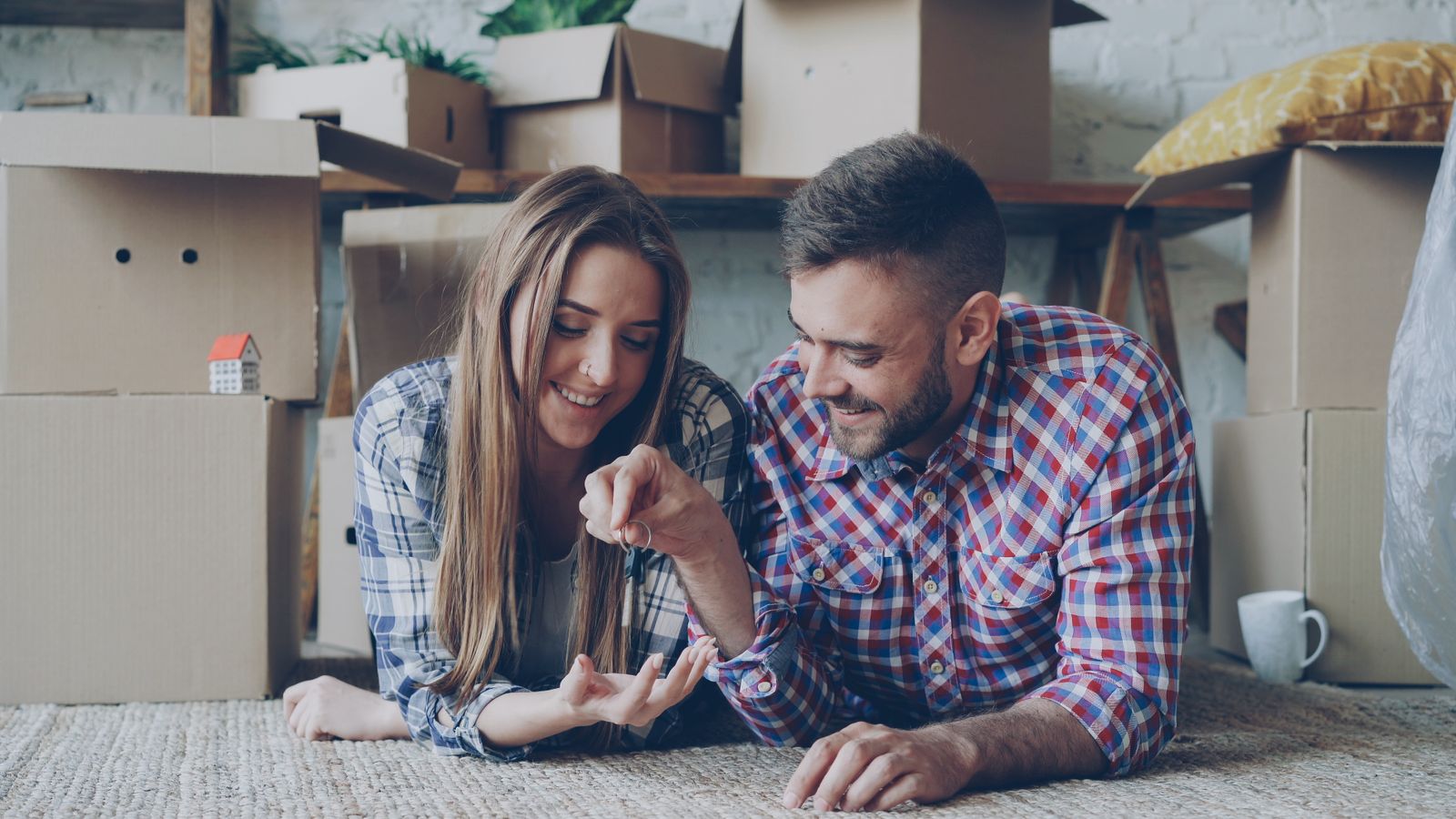 Couple holding their new keys among packed moving boxes