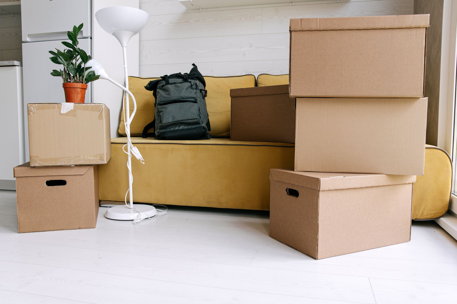 Moving boxes and a bag packed beside a sofa in a living room