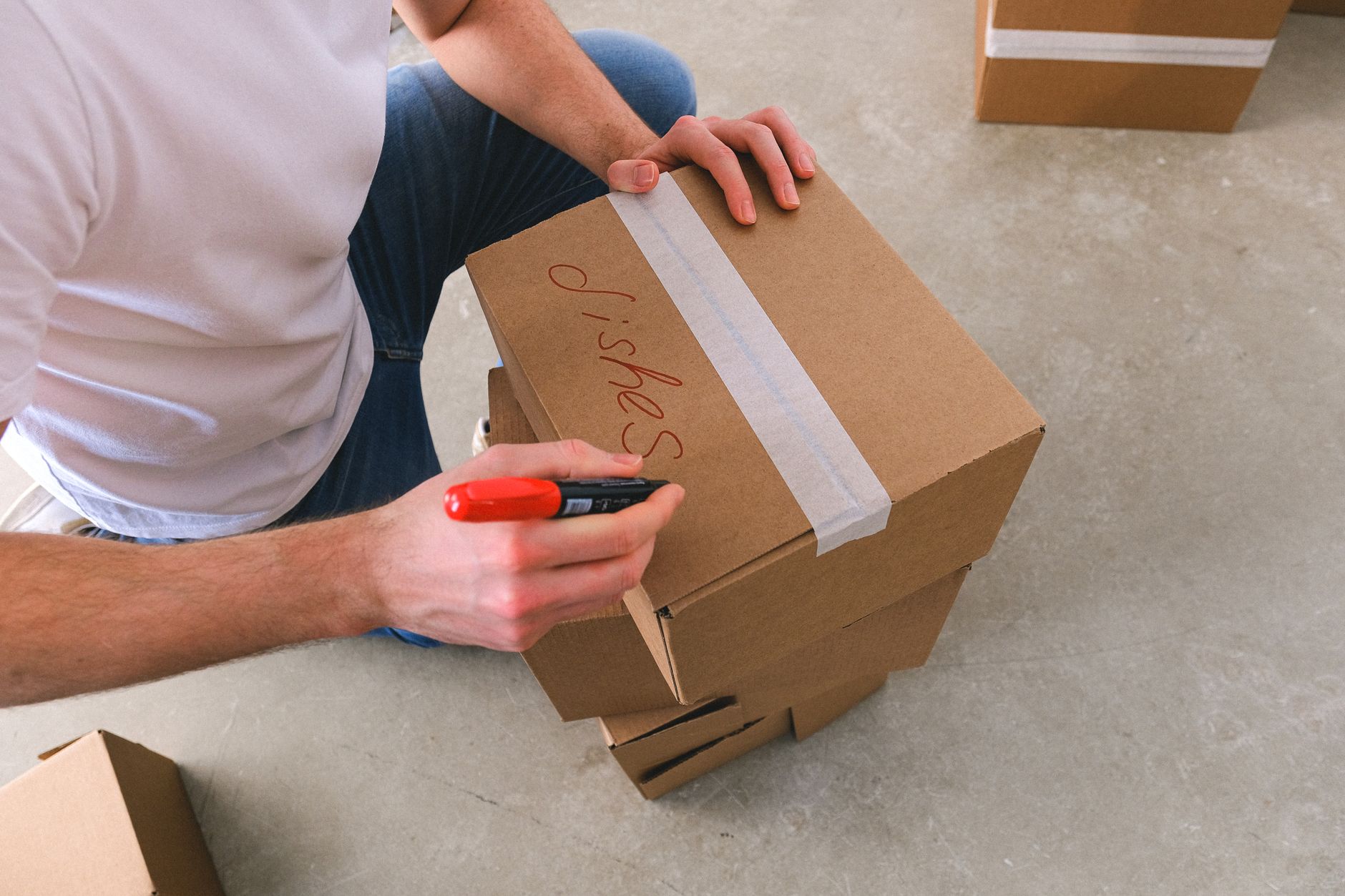 A person writing a contents label on a sealed moving box