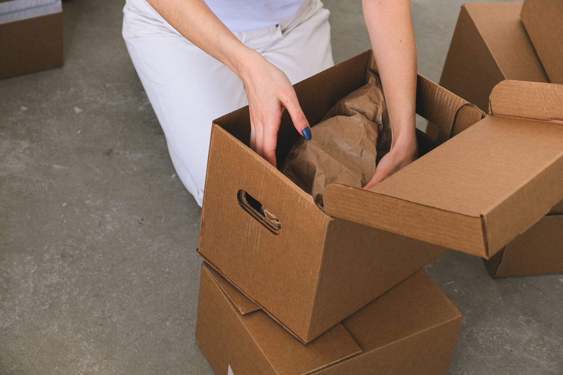 A student packing a protected item into a cardboard moving box